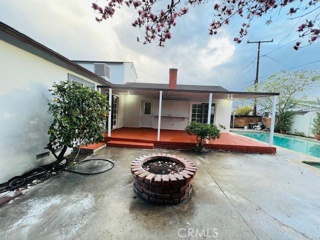 back of house with a patio, a pool side deck, and an outdoor fire pit