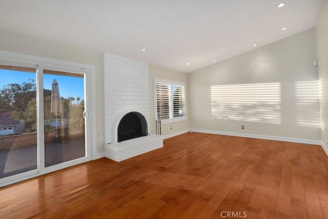 unfurnished living room featuring lofted ceiling, a fireplace, and hardwood / wood-style floors