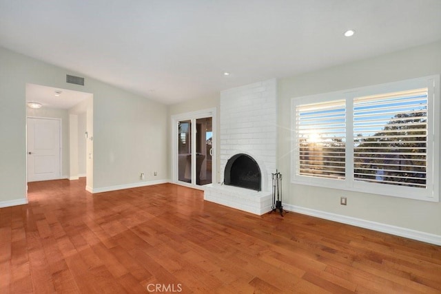 unfurnished living room with hardwood / wood-style flooring, lofted ceiling, and a fireplace