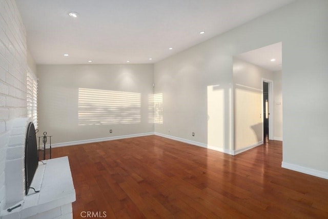 unfurnished living room featuring a brick fireplace and dark hardwood / wood-style flooring