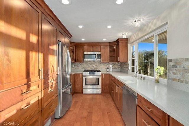 kitchen featuring light wood-type flooring, backsplash, sink, and stainless steel appliances