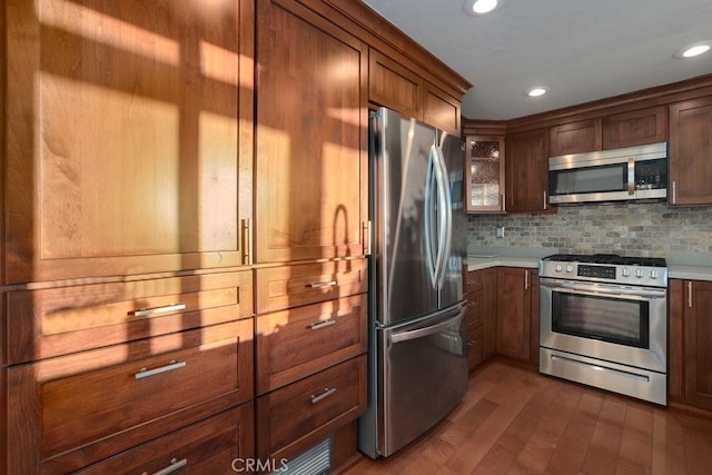 kitchen featuring decorative backsplash, appliances with stainless steel finishes, and dark hardwood / wood-style floors