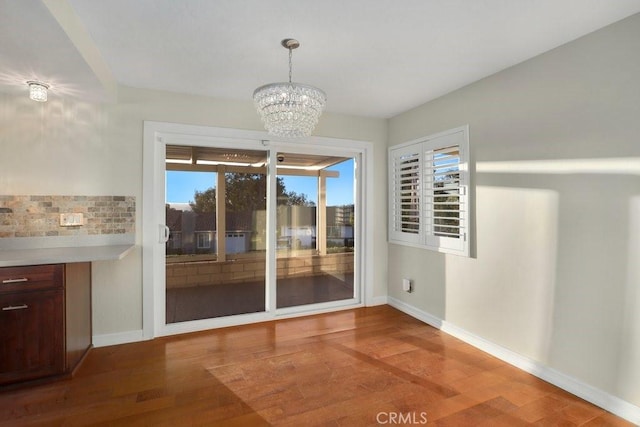 unfurnished dining area featuring hardwood / wood-style flooring and an inviting chandelier