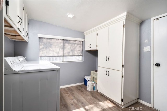 clothes washing area featuring cabinets, light wood-type flooring, and washing machine and clothes dryer