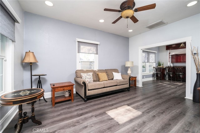 living room featuring ceiling fan, indoor bar, and dark wood-type flooring