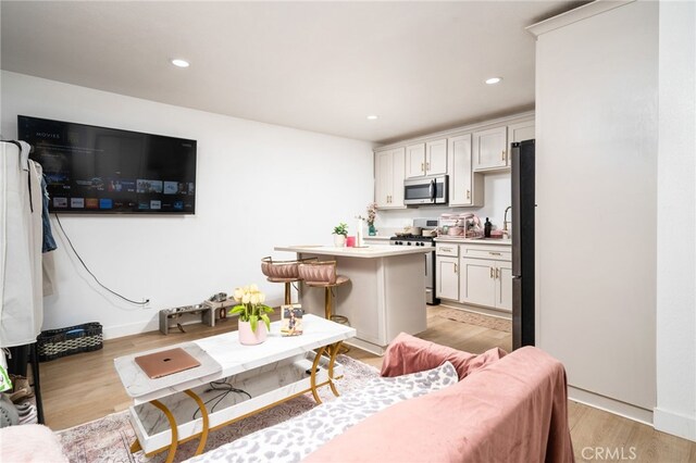 kitchen featuring a center island, a kitchen bar, light hardwood / wood-style flooring, stainless steel appliances, and white cabinets