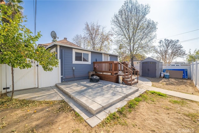 rear view of house featuring a wooden deck, a patio area, and a storage shed