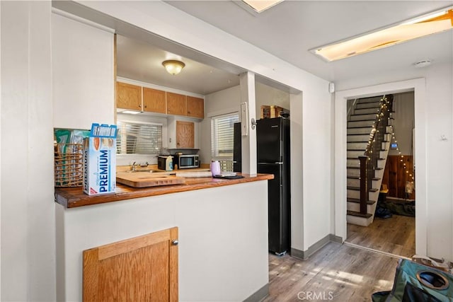 kitchen featuring black refrigerator, butcher block counters, and hardwood / wood-style flooring