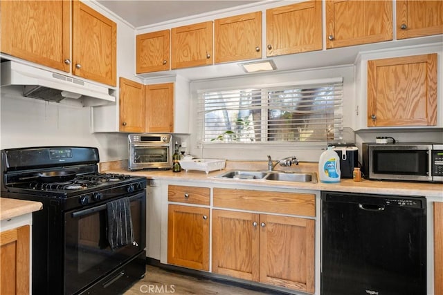 kitchen featuring black appliances, wood-type flooring, and sink