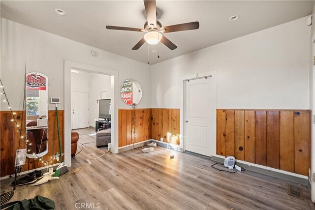 interior space featuring ceiling fan, hardwood / wood-style floors, and wood walls