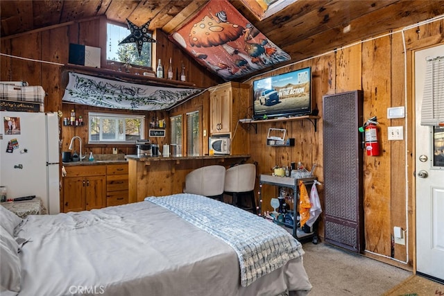 carpeted bedroom with white fridge, vaulted ceiling, wood walls, and sink