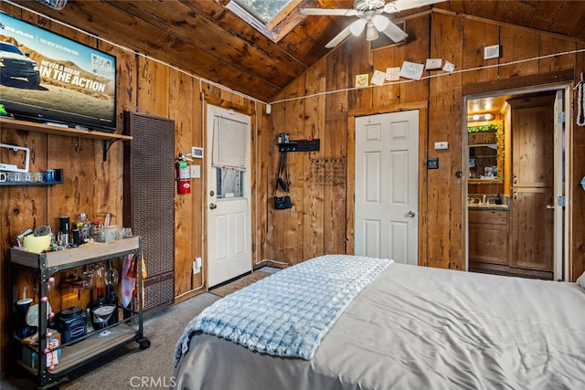 carpeted bedroom featuring ceiling fan, vaulted ceiling with skylight, wood ceiling, and wooden walls