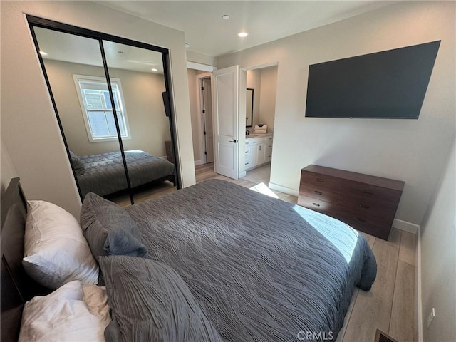 bedroom with connected bathroom, a closet, and light wood-type flooring