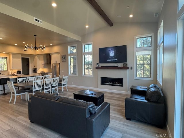 living room with lofted ceiling with beams, light wood-type flooring, and an inviting chandelier