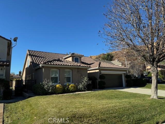 mediterranean / spanish-style home with a front lawn and a garage