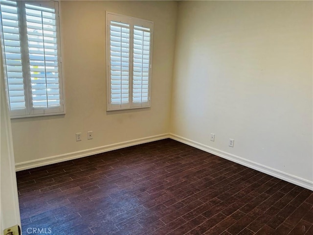 empty room featuring a wealth of natural light and dark hardwood / wood-style floors