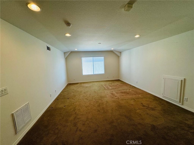 carpeted empty room featuring lofted ceiling and a textured ceiling