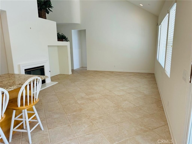 unfurnished living room with high vaulted ceiling and light tile patterned flooring