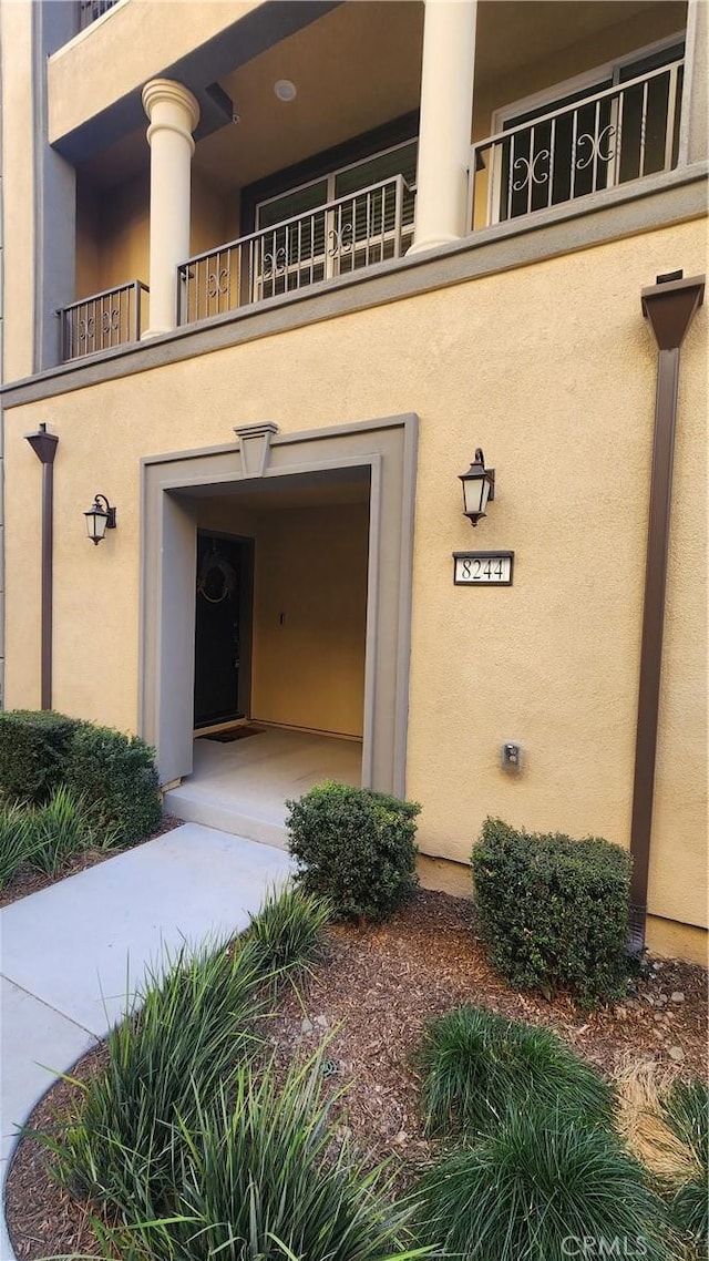 view of exterior entry featuring a garage and a balcony