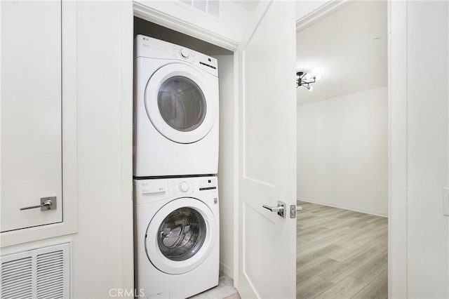 washroom featuring stacked washer / dryer and light hardwood / wood-style floors