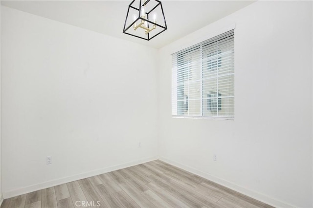 unfurnished room featuring an inviting chandelier and light hardwood / wood-style floors