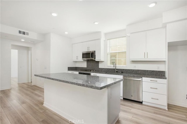 kitchen featuring white cabinetry, sink, a center island, stainless steel appliances, and light wood-type flooring