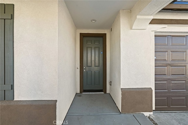 view of exterior entry featuring a garage and stucco siding