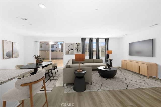 living area featuring light wood-type flooring and visible vents