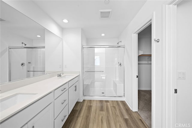 bathroom with a sink, wood finished floors, a shower stall, and visible vents