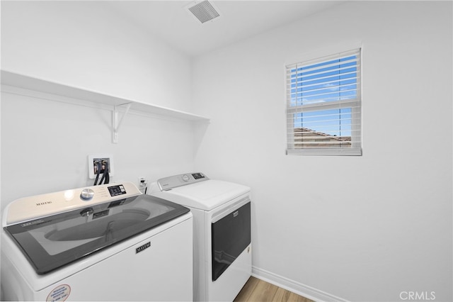 clothes washing area featuring light hardwood / wood-style floors and separate washer and dryer