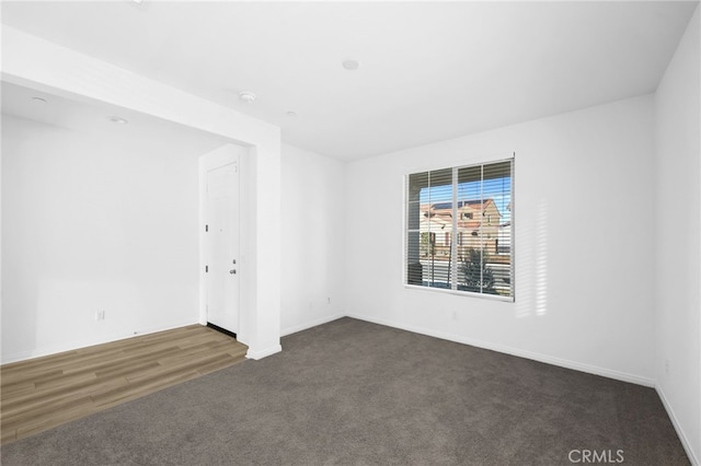 empty room with dark colored carpet and baseboards