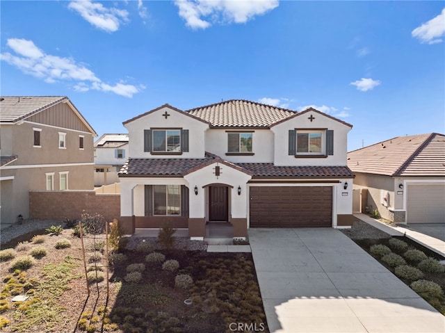 mediterranean / spanish-style home featuring a garage, a tile roof, fence, concrete driveway, and stucco siding