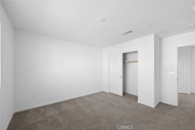 unfurnished bedroom with a closet, carpet, visible vents, and baseboards