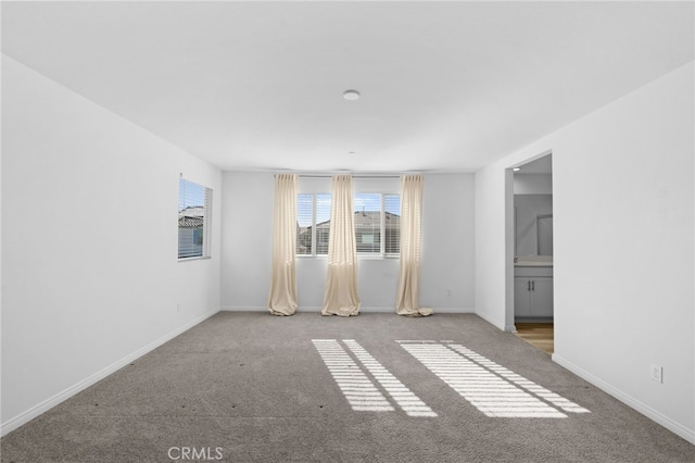 unfurnished room with carpet and baseboards