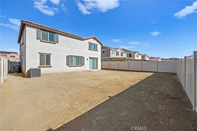 rear view of house with central AC, a fenced backyard, and stucco siding