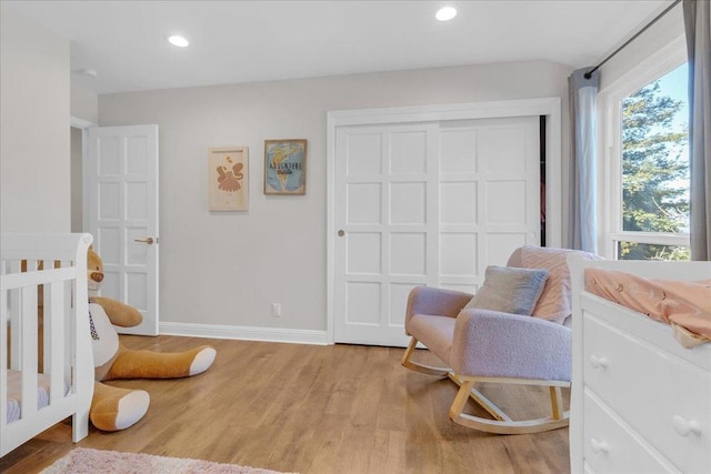 bedroom with light wood-type flooring and a crib