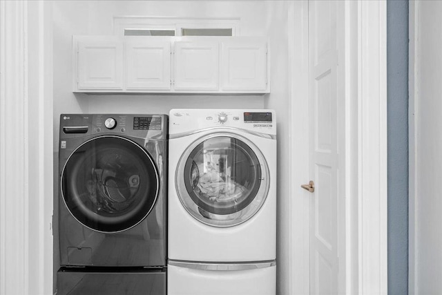 clothes washing area with cabinets and washer and dryer