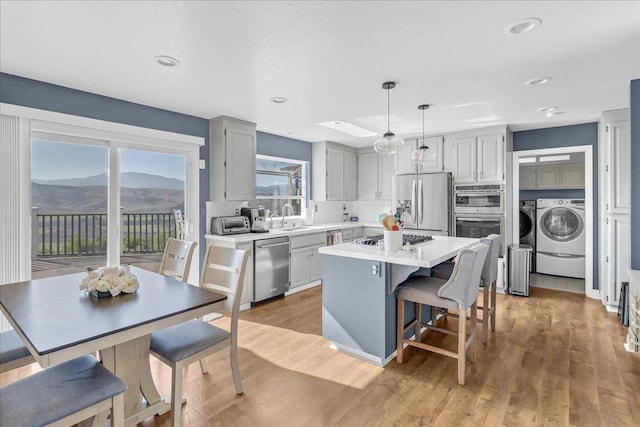 kitchen featuring sink, a center island, light wood-type flooring, appliances with stainless steel finishes, and pendant lighting