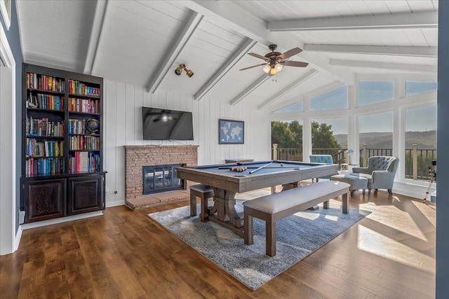 playroom featuring billiards, ceiling fan, vaulted ceiling with beams, a fireplace, and dark hardwood / wood-style flooring