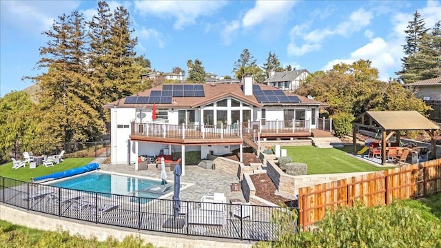 rear view of property with solar panels, a pool side deck, a yard, an outdoor living space, and a patio area