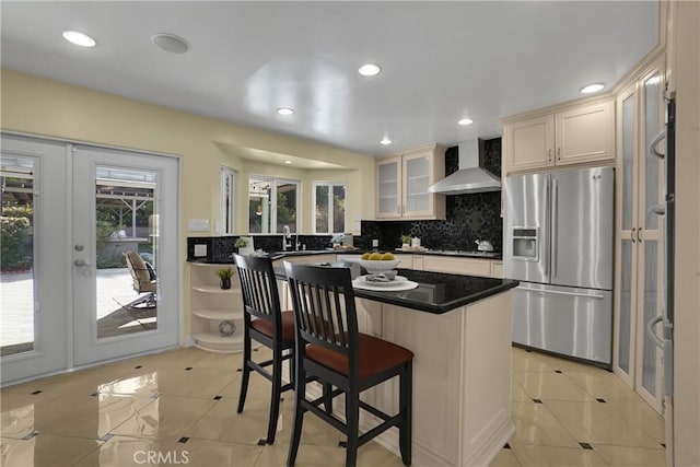 kitchen featuring a wealth of natural light, stainless steel appliances, a kitchen island, and wall chimney range hood