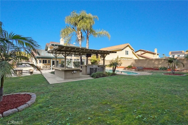 back of house featuring exterior kitchen, a patio area, exterior bar, a fenced in pool, and a lawn