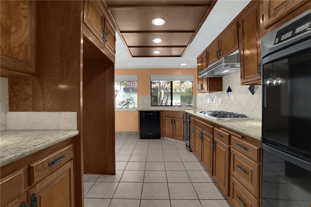 kitchen featuring black appliances, tasteful backsplash, sink, light tile patterned flooring, and light stone counters