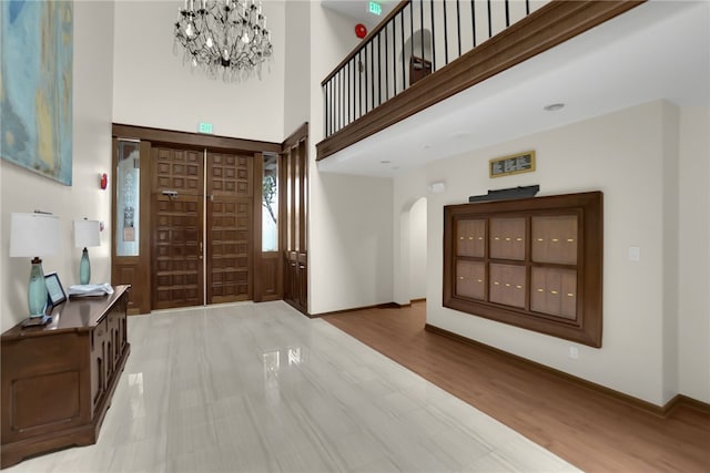 foyer entrance with a high ceiling, an inviting chandelier, and light hardwood / wood-style floors