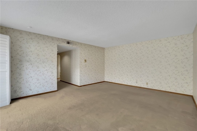 unfurnished room with light colored carpet and a textured ceiling