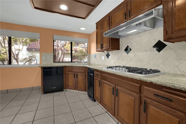 kitchen featuring stainless steel gas stovetop, sink, light tile patterned flooring, black dishwasher, and light stone countertops