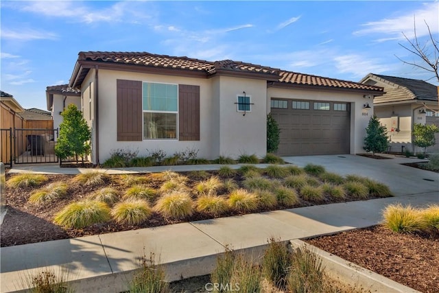 mediterranean / spanish house with a tile roof, stucco siding, fence, a garage, and driveway