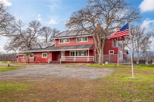 view of front facade with a front lawn, solar panels, and a porch