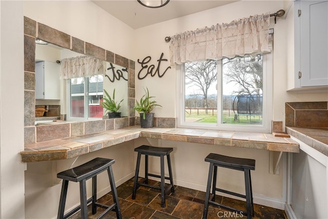 kitchen featuring a kitchen breakfast bar, a wealth of natural light, and white cabinets