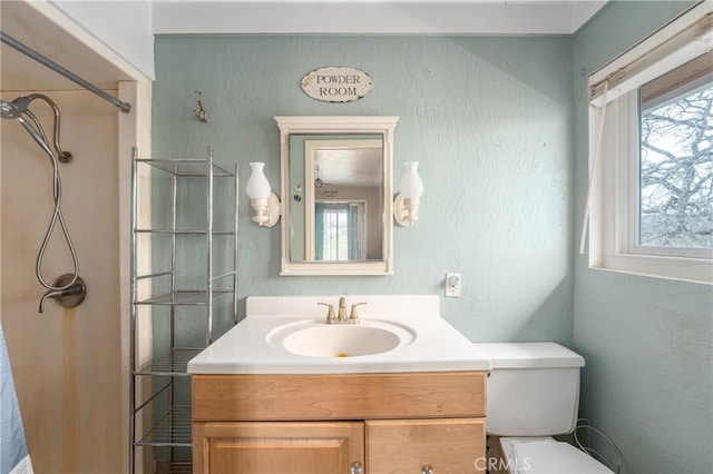 bathroom featuring toilet, a shower, and vanity